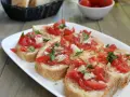 Fette di pane tostato condite con pomodoro fresco, cipolla e basilico, un classico della panzanella romana.