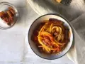 Un piatto invitante di bucatini all'amatriciana, con guanciale croccante e una salsa rossa saporita, spolverato di formaggio grattugiato.