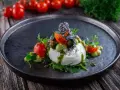 Burrata affumicata con pomodorini, crema di piselli, pinoli e pesto. Un piatto che esalta gli abbinamenti perfetti.