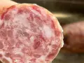 Fetta di cotechino, un salume cotto, mostra la sua carne macinata con grasso e cotenna.