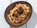 Piatto di pasta con fagioli e cozze, condita con pomodorini e una cremosa salsa.
