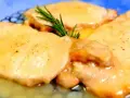 Deliziose scaloppine di maiale in salsa dorata, guarnite con un rametto di rosmarino fresco.