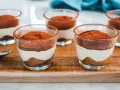 Delizioso tiramisù con pavesini senza uova, servito in bicchierini trasparenti e spolverato di cacao.