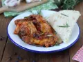 Piatto di friccò di pollo con pomodoro, olive e rosmarino, accompagnato da pane rustico.