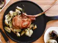 Un succulento tomahawk alla griglia, servito con verdure arrosto su un piatto nero.