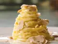 Un nido di pasta al tartufo, condita con una cremosa salsa e guarnita con scaglie sottili di tartufo bianco.