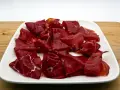 Fetta di bresaola scura, forse di cavallo, su un piatto bianco. Meglio bresaola di cavallo o manzo? La scelta è tua!