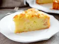 Una fetta di torta margherita con mele, soffice e dorata, servita su un piatto bianco.