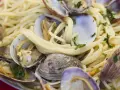 Un piatto invitante di spaghetti alle vongole, con pasta dorata e molluschi freschi guarniti da prezzemolo tritato.