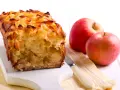 Torta con pandoro avanzato e mele, dorata e profumata, accanto a mele rosse fresche.