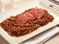 Piatto di lenticchie con fette di cotechino, un classico della tradizione.
