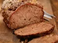 Un succulento polpettone al forno, tagliato a fette su un tagliere di legno, pronto per essere gustato.