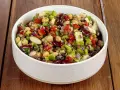 Una ciotola piena di colorata insalata di legumi, con ceci, fagioli, lenticchie, peperoni, cipolla rossa e prezzemolo fresco.
