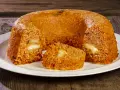 Un invitante timballo di riso, dorato e ripieno di formaggio filante, pronto per essere gustato su un piatto bianco.