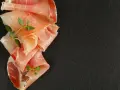 Fettine di prosciutto crudo e speck, con rametti di timo, per mostrare la differenza tra speck e prosciutto crudo.