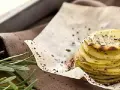 Deliziosa torretta di patate, sottili fette impilate e condite con erbe aromatiche e pepe nero, su carta da forno.