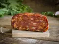Un pezzo di salame stagionato su tagliere di legno. La differenza tra salame e sopressa è nella grana: qui si vede la carne tritata grossolanamente.