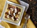 Carciofi e ricotta al forno in una teglia bianca, guarniti con pangrattato croccante. Serviti su un tovagliolo giallo.
