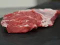 Un succulento spider steak crudo, con venature di grasso bianco, pronto per essere cucinato su una pietra scura.