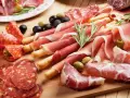 Tagliere con salumi misti, tra cui affettati non di maiale, olive e rosmarino.