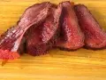 Fette succulente di spinacino di manzo, cotte alla perfezione, adagiate su un tagliere di legno.