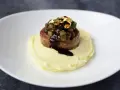 Piatto moderno con lenticchie e cotechino, un omaggio alla tradizione, servito su purè di patate e decorato con oro edule.