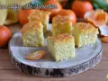 Fette di torta di clementine soffice, guarnite con scorza d'arancia, su un tagliere di legno.