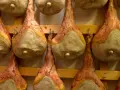 Filetti di salumi appesi a stagionare su scaffali di legno.