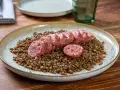 Piatto di lenticchie con fette di cotechino fatto in casa, un classico confortante.