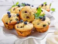 Muffin ai mirtilli appena sfornati, decorati con mirtilli freschi e menta. Una deliziosa ricetta per iniziare la giornata.