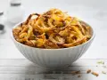 Ciotola piena di croccanti cipolle fritte dorate, perfette per accompagnare ogni piatto.
