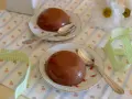 Due budini al cioccolato con amido di mais, serviti su piattini floreali con cucchiaini d'argento. Nastro a quadretti verdi completa la scena.