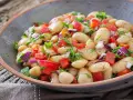 Insalata di fagioli bianchi, pomodori freschi, cipolla rossa e erbe aromatiche in una ciotola rustica. Un piatto colorato e salutare.
