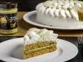 Una fetta di torta soffice al pistacchio, con crema al pistacchio e panna montata. Accanto, un barattolo di crema al pistacchio.