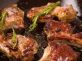 Succulento agnello in padella, dorato e profumato con rosmarino e pepe.