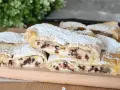 Rotolo di sfoglia con ricotta dolce e gocce di cioccolato, spolverato di zucchero a velo, su un tagliere di legno.
