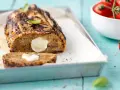 Polpettone di melanzane grigliato, ripieno di formaggio filante, su teglia con basilico e pomodorini.