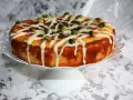 Deliziosa torta al bergamotto, decorata con glassa bianca e pistacchi croccanti, pronta per essere gustata.