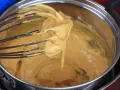 Una frusta raccoglie una crema densa e dorata, pronta per diventare uno zabaione freddo.