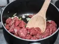 Bocconcini di manzo crudo in padella con cipolla, pronti per diventare uno spezzatino gommosa di manzo.