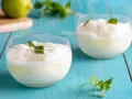 Sorbetto al limone senza gelatiera: due coppette di fresco sorbetto al limone guarnite con menta, su un tavolo di legno blu.