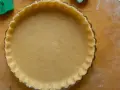 Base di pasta frolla veloce pronta per essere farcita, con bordi decorati e forata per una cottura perfetta.