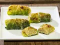 Cinque capunet piemontesi, involtini di verza ripieni, serviti su un piatto bianco.