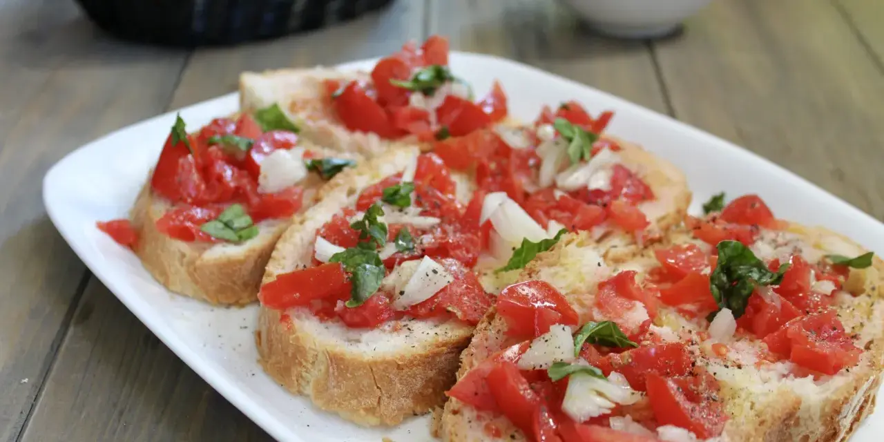 Fette di pane tostato condite con pomodoro fresco, cipolla e basilico, un classico della panzanella romana.