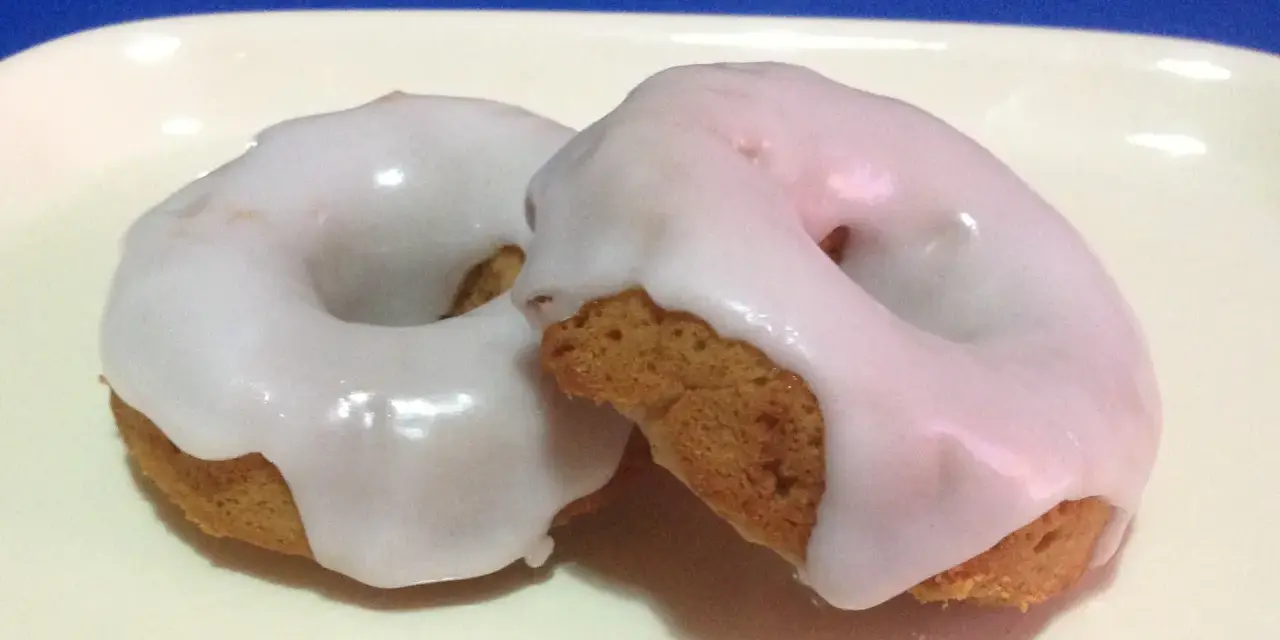 Due ciambelle con glassa di zucchero bianca e lucida, perfette per chi vuole imparare come fare la glassa di zucchero.