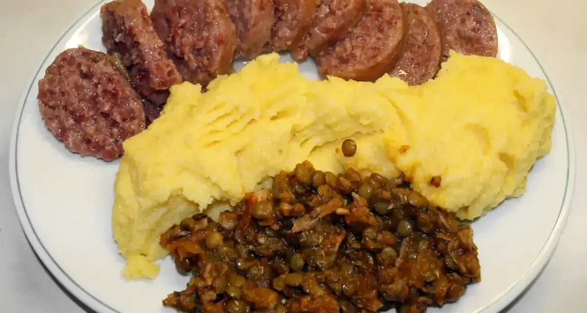 Piatto con fette di cotechino o musetto, polenta gialla e lenticchie stufate.