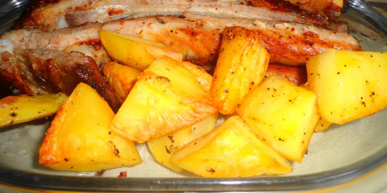 Costine di maiale al forno con patate dorate, un piatto succulento e saporito, pronto per essere gustato.