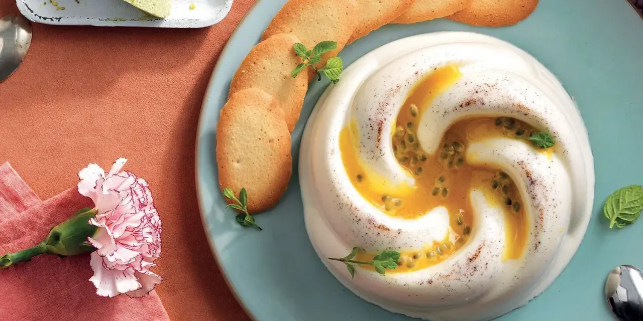 Dolce cremoso con cuore di frutto della passione, guarnito con biscotti e menta.