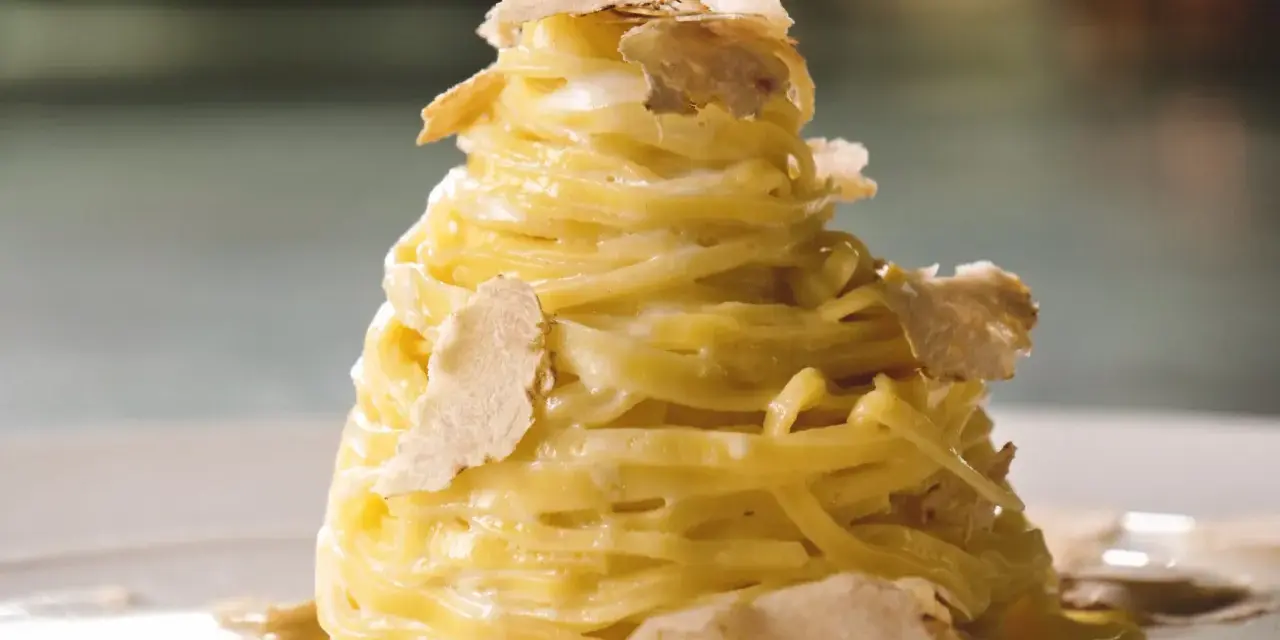 Un nido di pasta al tartufo, condita con una cremosa salsa e guarnita con scaglie sottili di tartufo bianco.