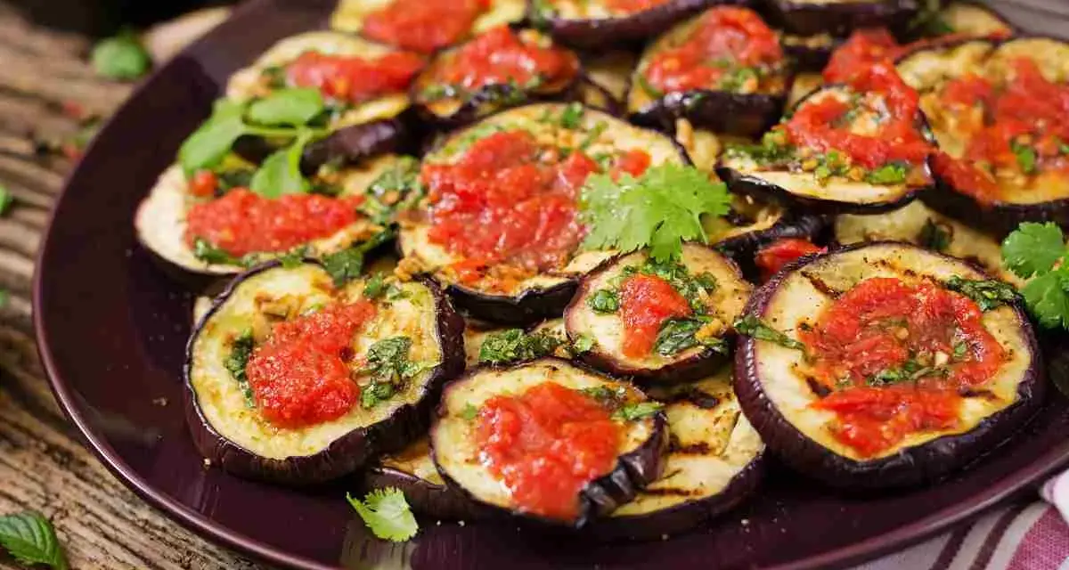 Fette di melanzane grigliate condite con salsa di pomodoro e basilico, un piatto gustoso di melanzane alla pizzaiola.